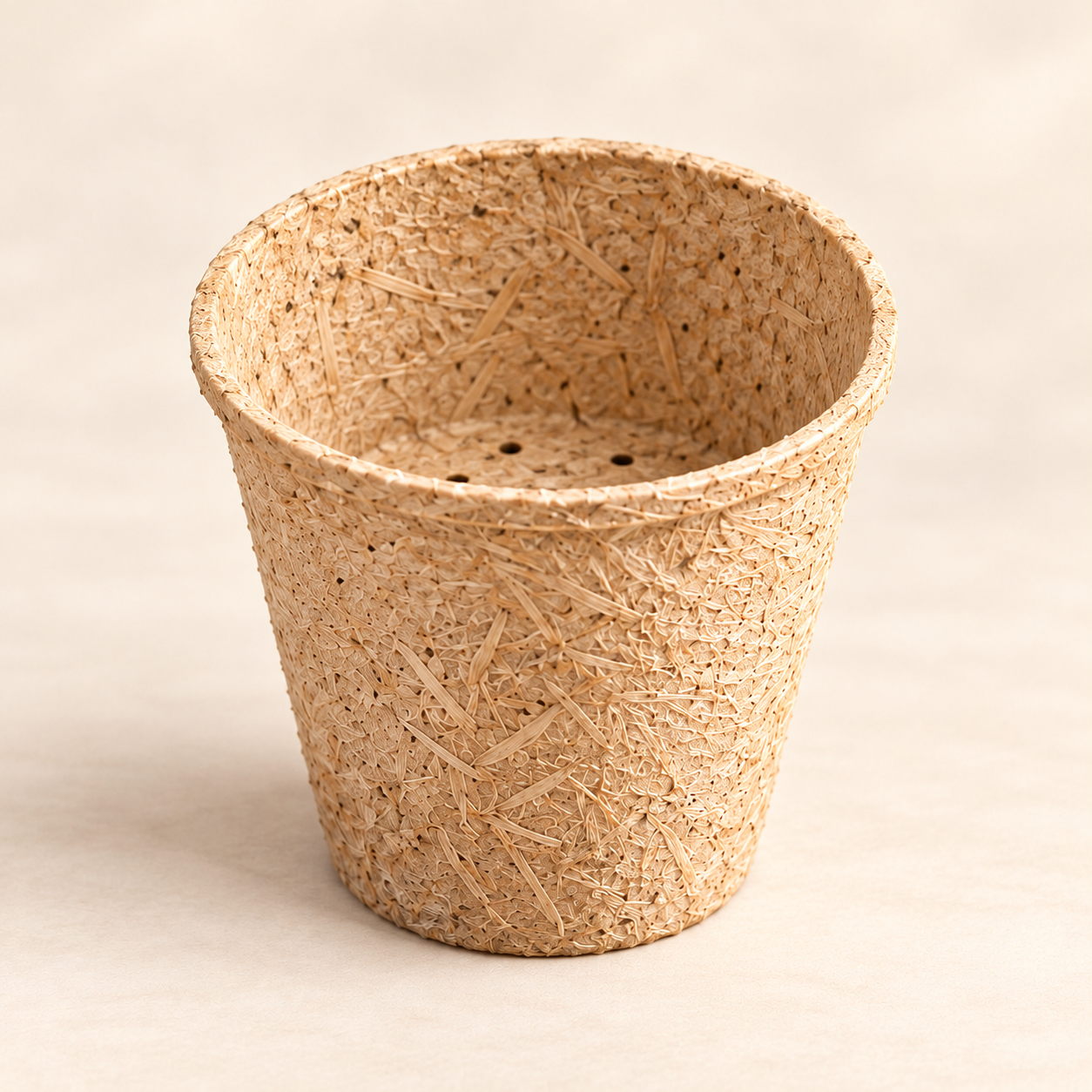 Prototipo conceptual de maceta vacía: textura de fibras agrícolas y orificios de drenaje